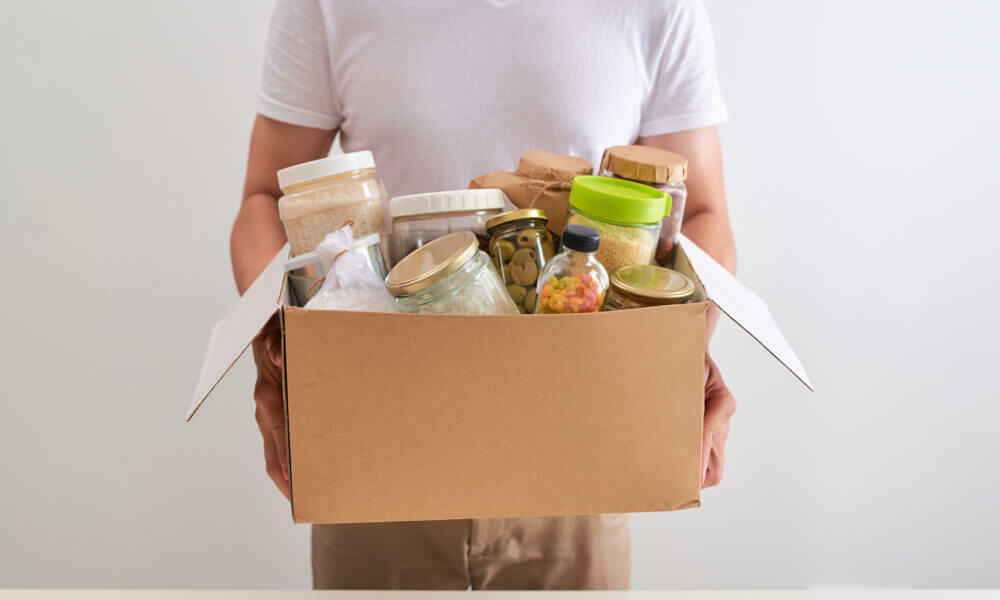 man holding box with different home stuff moving to a new modern house