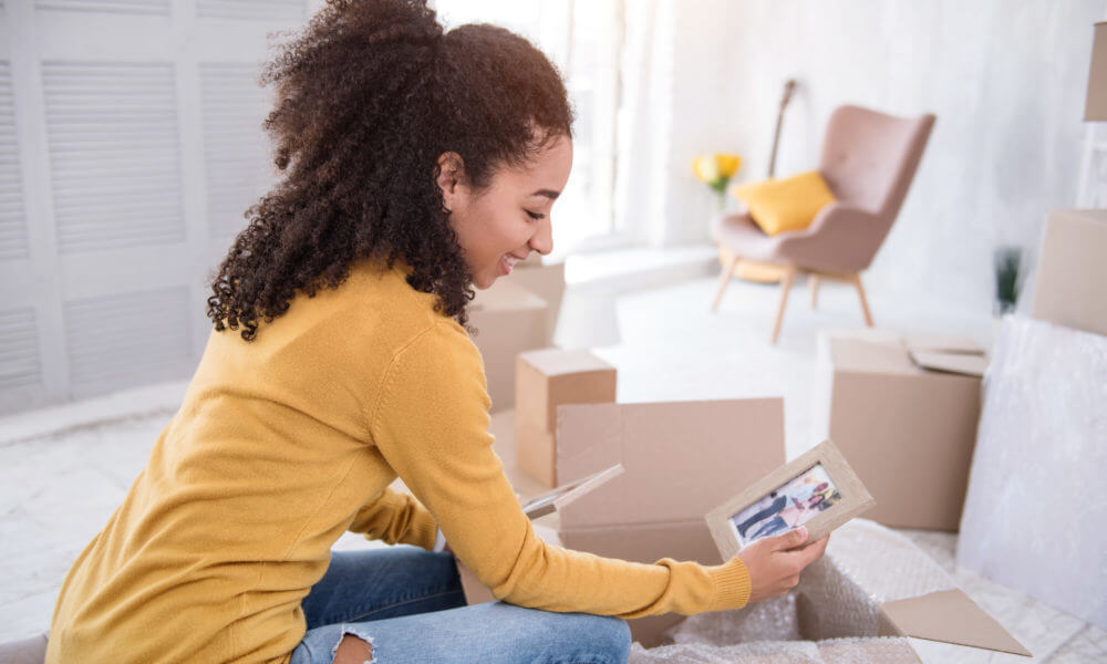 woman sitting between packaging boxes, looking at photo