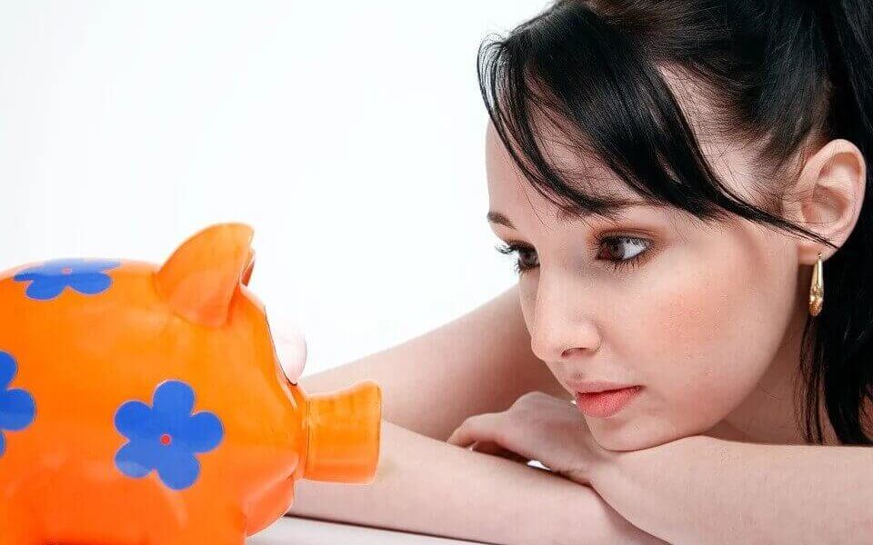 A woman looking at a piggy bank