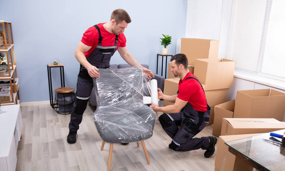 An image of two movers wrapping a chair.