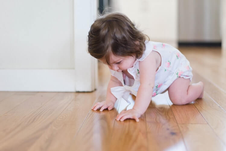 A girl crawling on the parquet floor