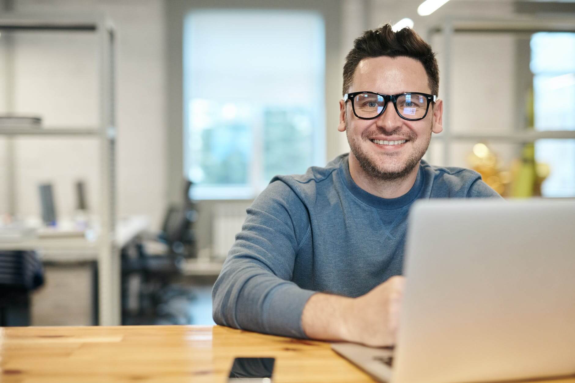 A man smiling in front of the laptop