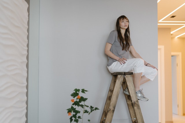 Girl sitting on a ladder, sad after a long-distance moving
