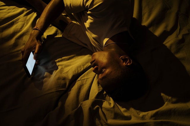 Man laying in bed looking at the phone after cross-country moving