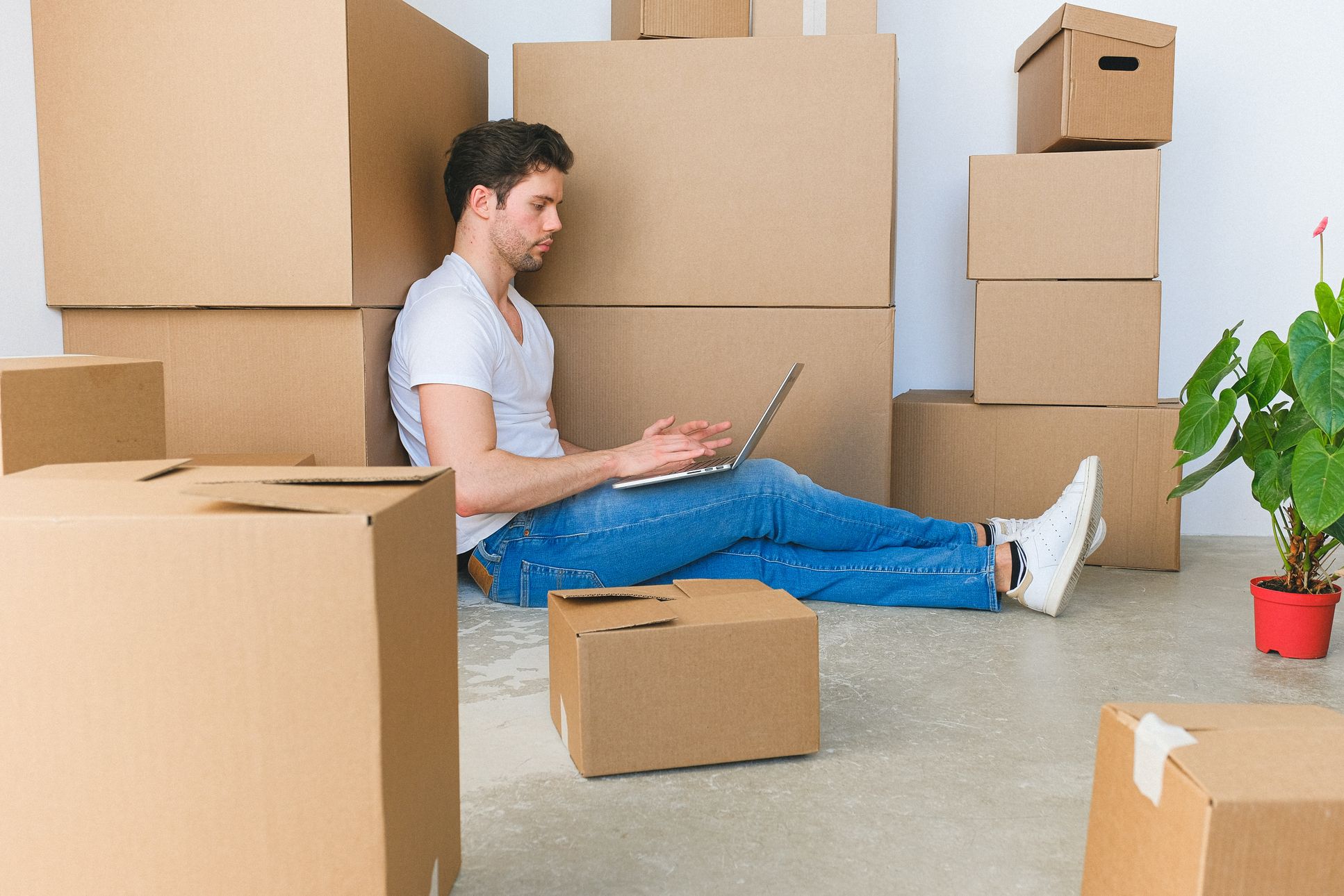 Man surrounded with boxes using a laptop for finding long-distance moving services