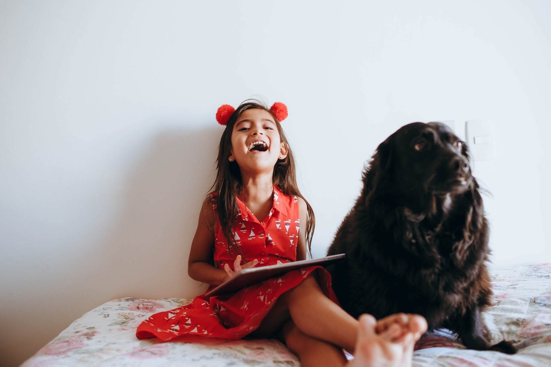A girl smiling with the dog on a bed