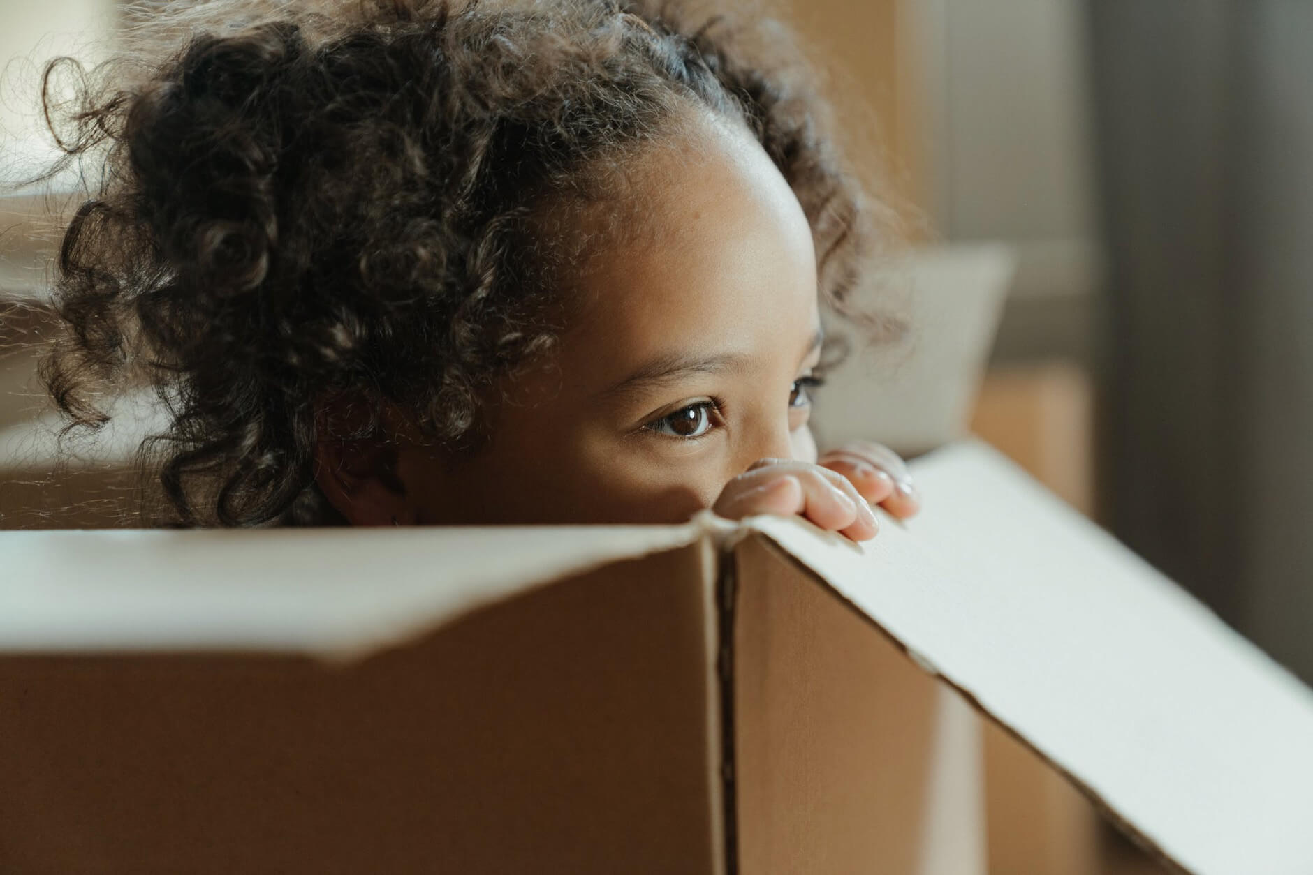 A kid hiding in a box while parents are packing for long-distance moving
