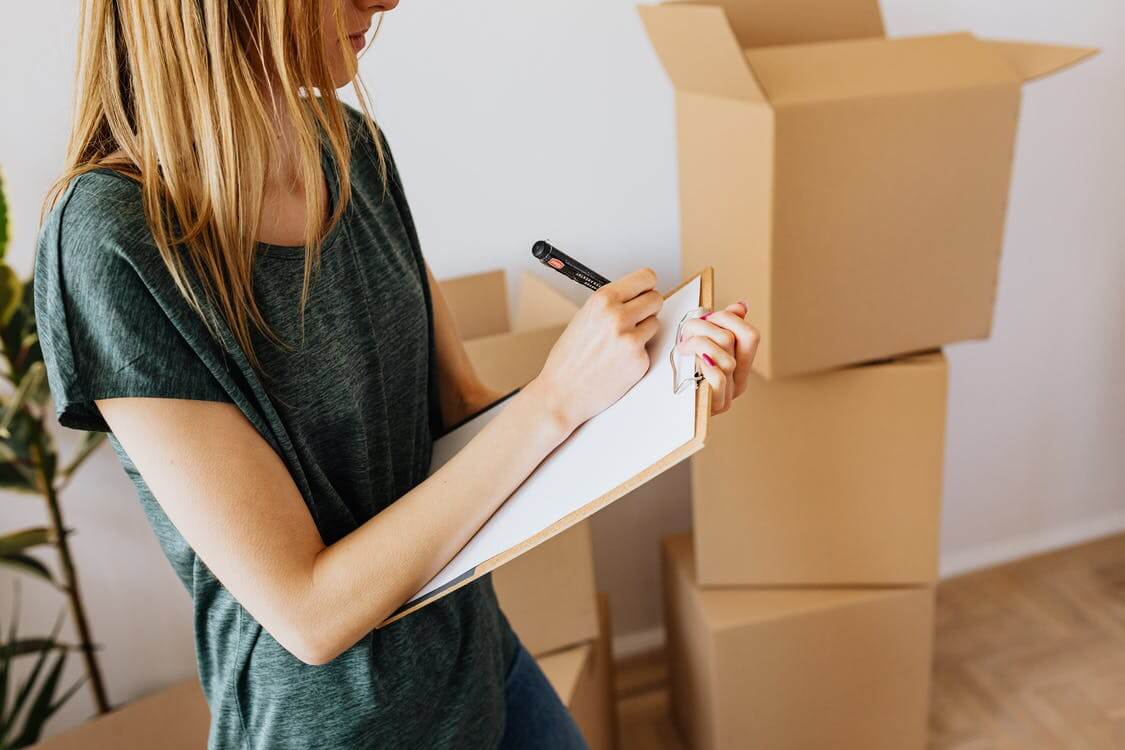 a girl is creating a packing list for long-distance moving