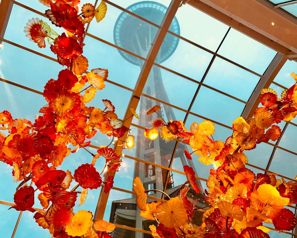 Vibrant red and yellow blown-glass flowers hanging from a glass window at Chihuly Garden and Glass in Seattle.