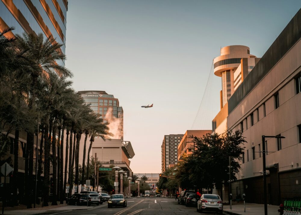Airplane flying low over city buildings and street.