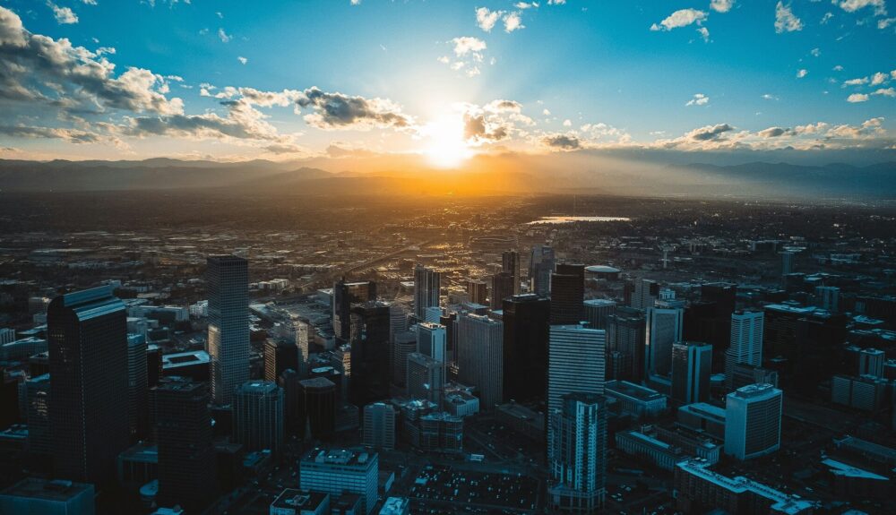 Golden sunset glowing over a dense city skyline with tall skyscrapers and buildings.